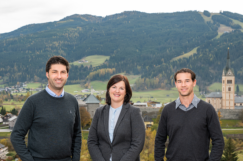 Das Team der UNIQA GeneralAgentur Mayrhofer und Walcher vor einer grünen Landschaft.